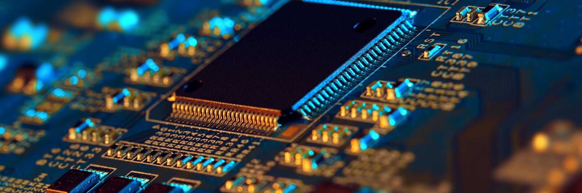 Close-up of an electronic circuit board featuring a central black microchip surrounded by various small components like resistors and capacitors. The board is illuminated with blue and orange lighting, highlighting its details. (This text has been generated by AI)