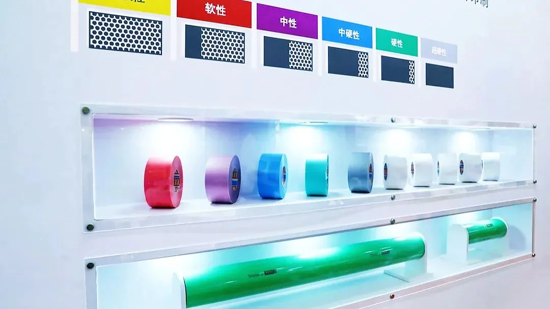 A display with shelves showing various colorful cylindrical objects under individual lights. The top shelf features four different colors, and the bottom shelf predominantly showcases green cylinders. Labels in multiple colors are positioned above, highlighting tesa tape as the featured brand. (This text has been generated by AI)