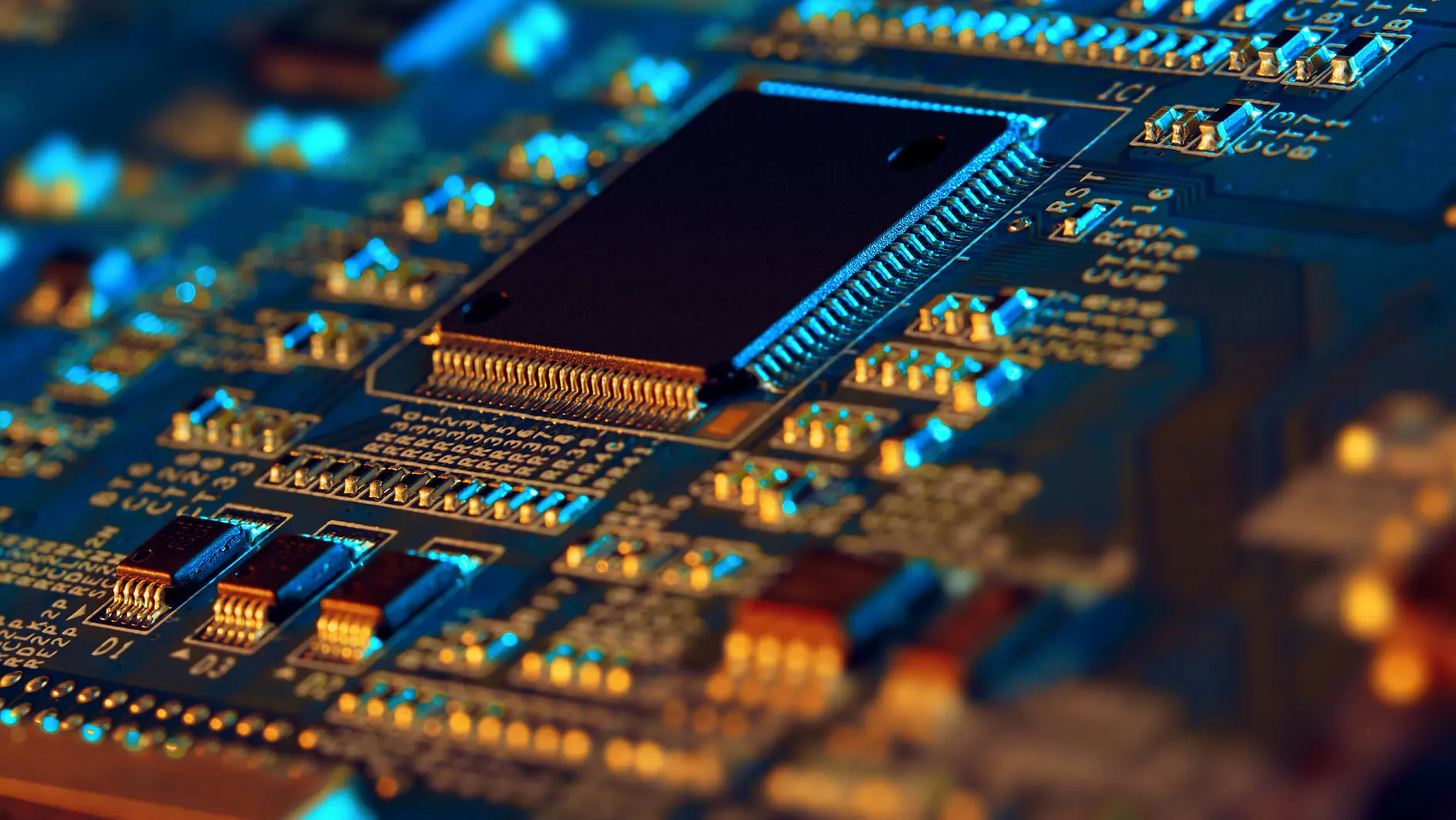 close-up of a black microchip mounted on a blue printed circuit board with various electronic components and gold connectors (This text has been generated by AI)