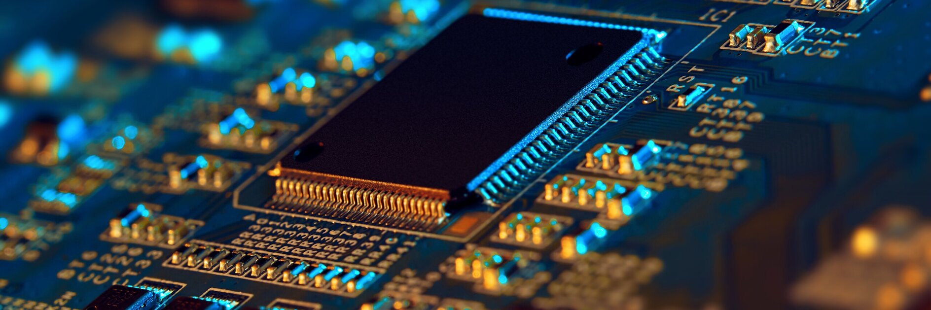 close-up of a black microchip mounted on a blue printed circuit board with various electronic components and gold connectors