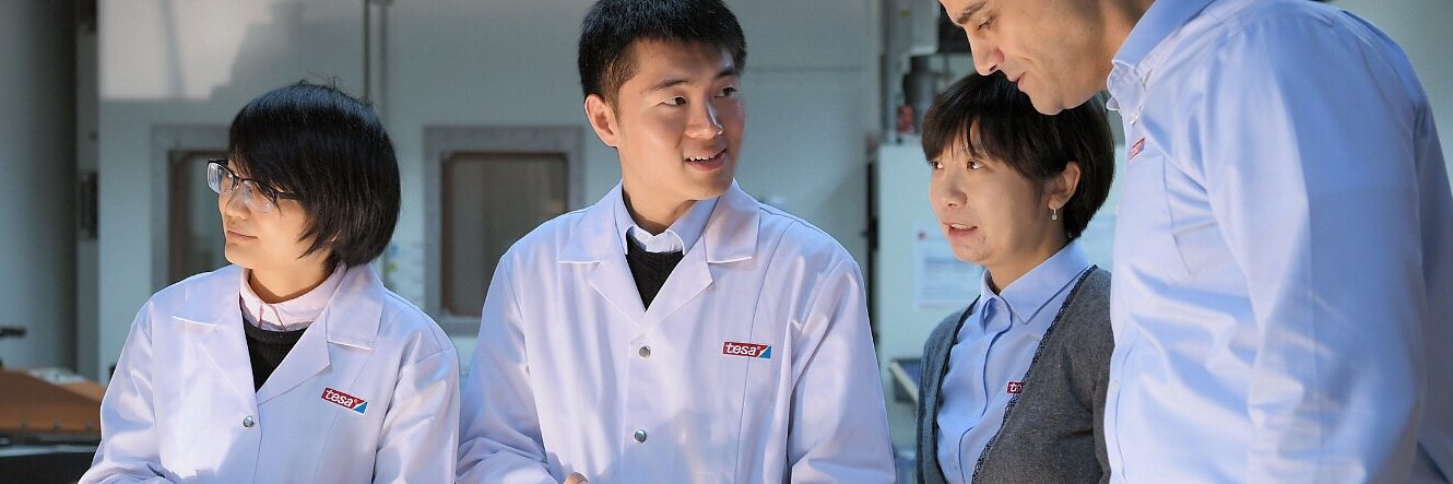 tesa lab technicians and professionals in white coats discussing and examining a device indoors in a laboratory setting
