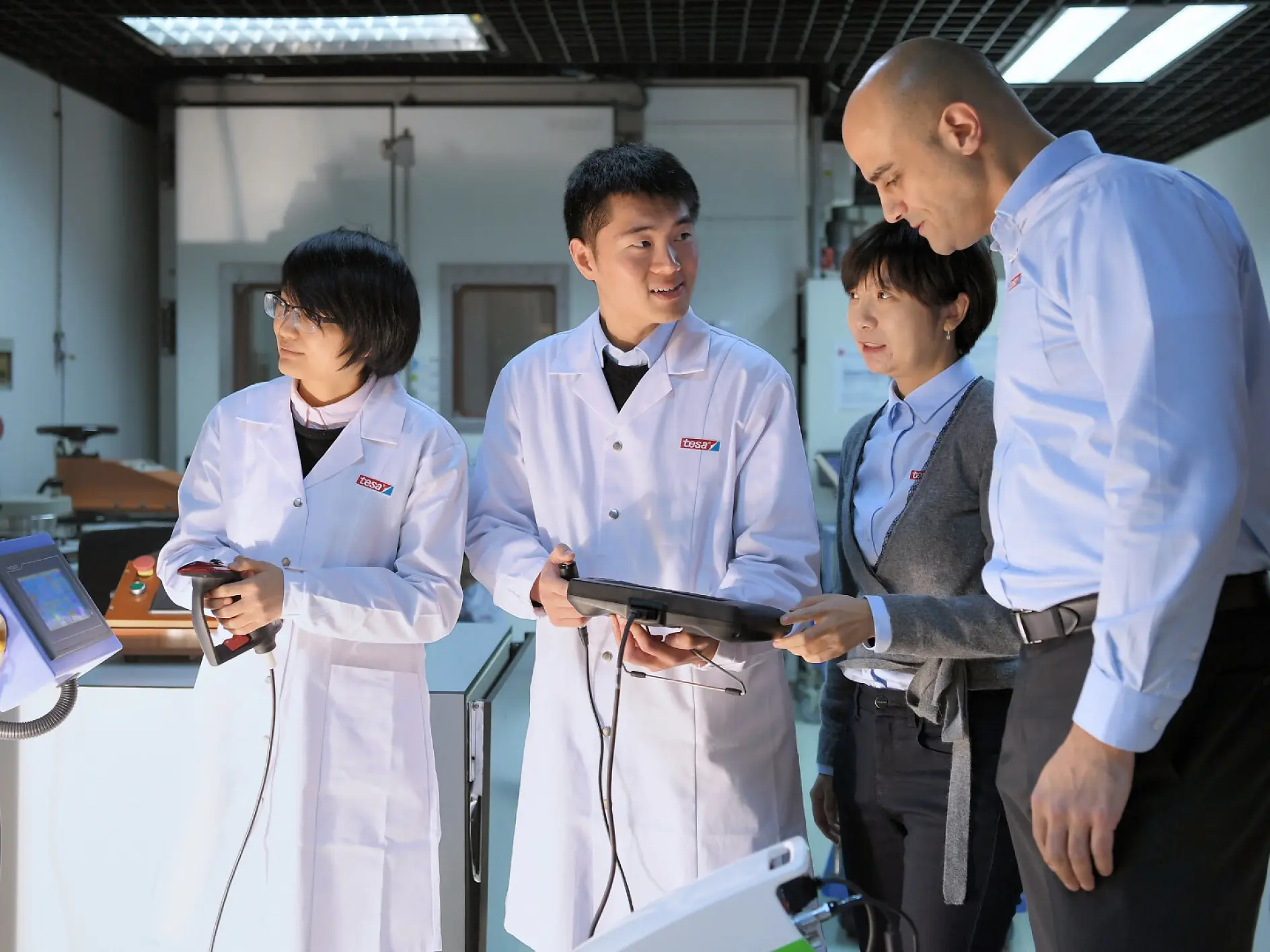 tesa lab technicians and professionals in white coats discussing and examining a device indoors in a laboratory setting (This text has been generated by AI)